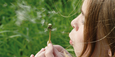 Petite fille souffle sur une fleur